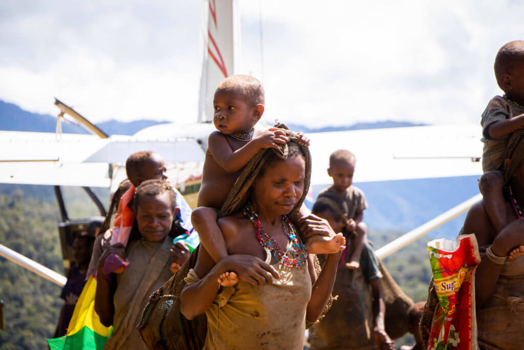 Moi parents and children in Papua Indonesia with Mission Aviation Fellowship charity airplane.