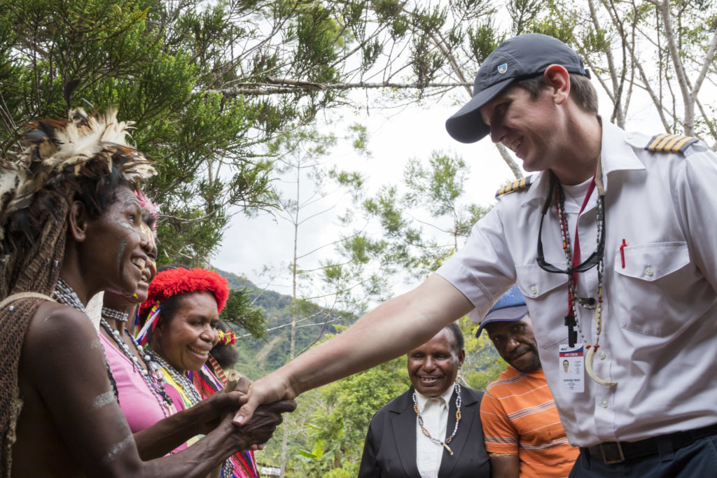 An MAF pilot shakes hands with a Yali woman during Bible dedication in Papua.